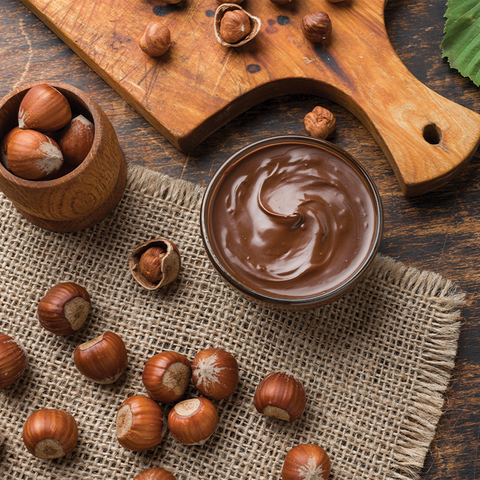 A bowl of chocolate paste in a bowl with a chopping board and cacao bean shell